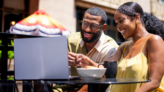 man and woman looking at a lap top and smiling